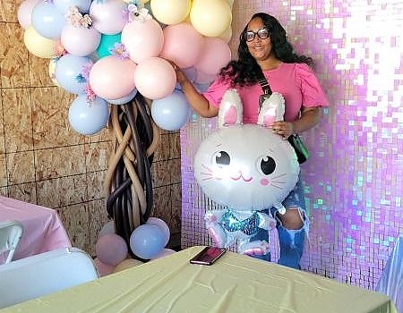 Guest holding balloon next to balloon tree at event