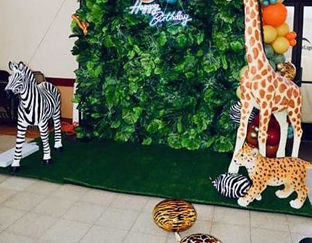Green wall with balloons and animals at event in Bay Area