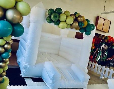 White inflatable castle with balloons at birthday event